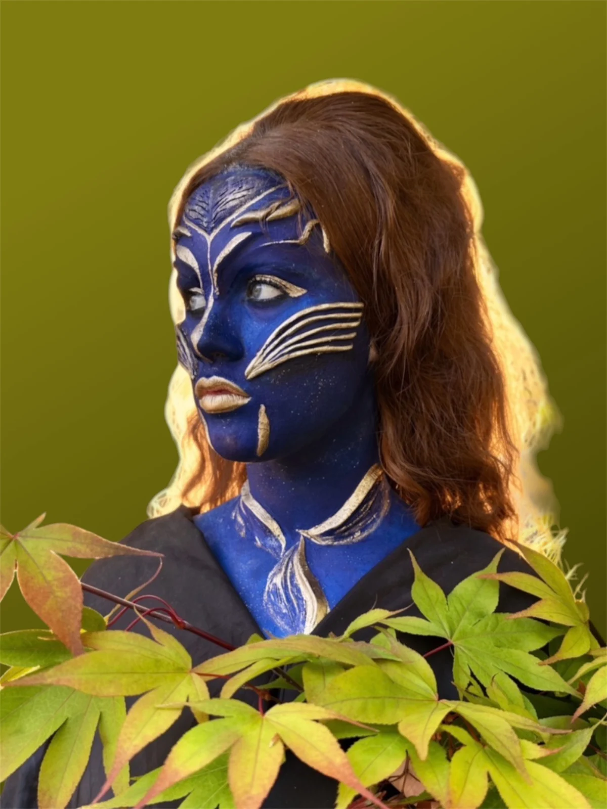 Fantasy character body paint in deep blue and gold with leaf details.