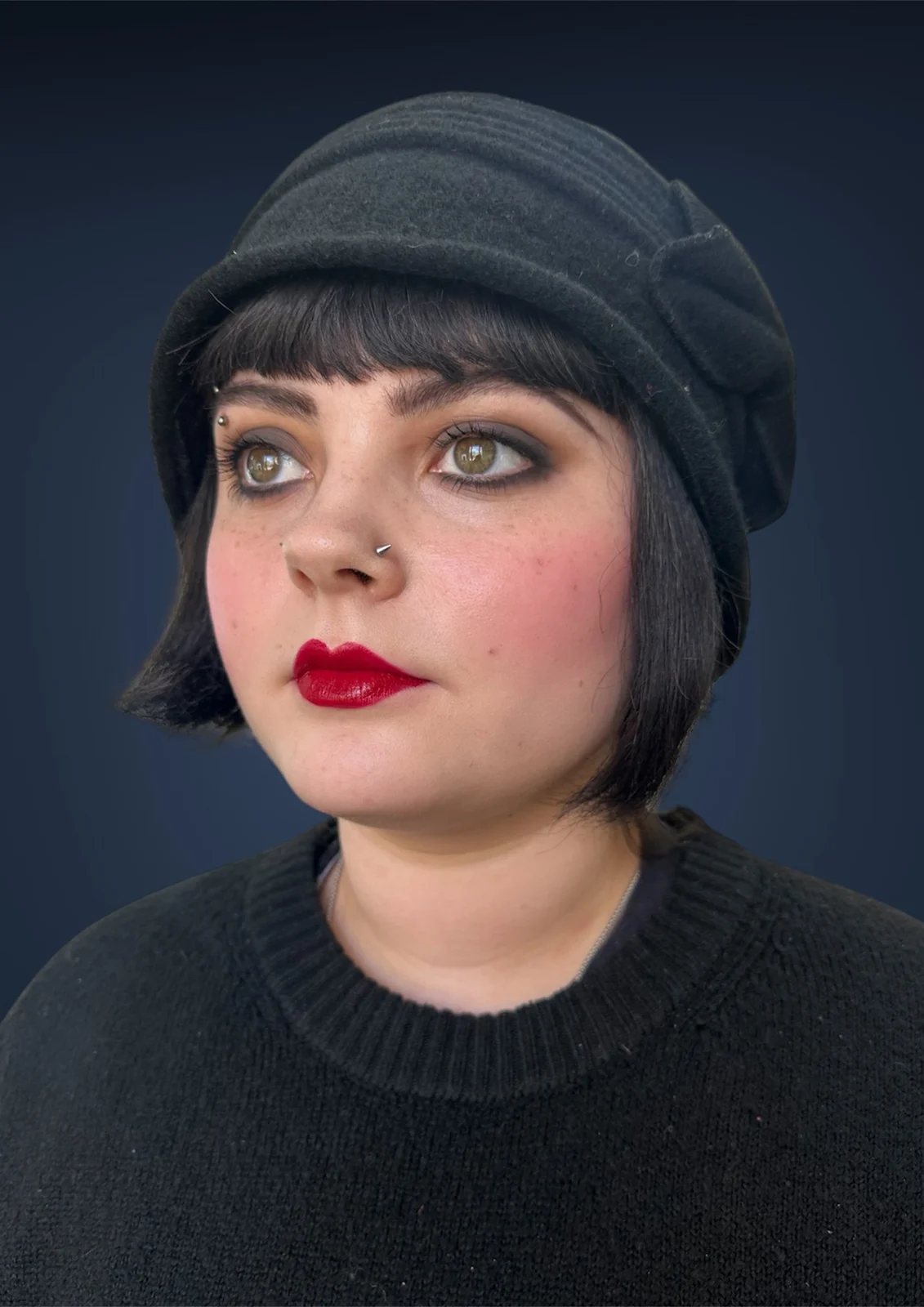 1930s inspired makeup with a defined red lip, waved bob and dark cloche hat.